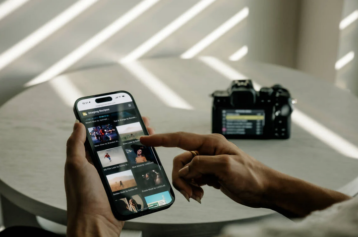 The new Nikon Z50II on a table, with a person holding a phone demonstrating the new app 