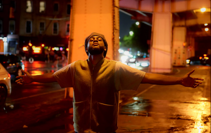Image of a person standing in the street, with a low light condition. 